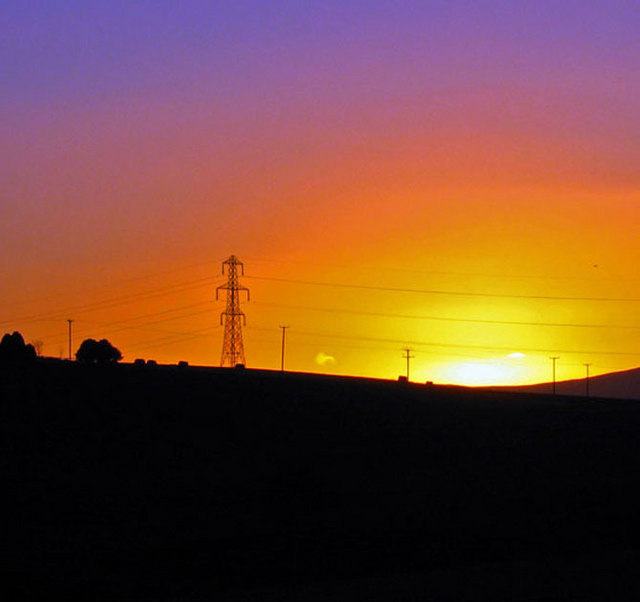 Power lines and a pylon at sunset